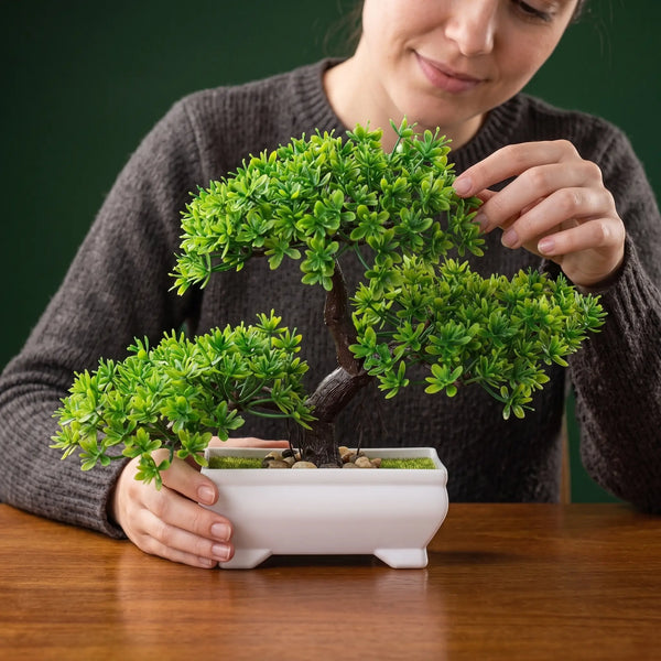Mulher segurando mini bonsai artificial decorativo verde em vaso branco, mostrando o tamanho do produto